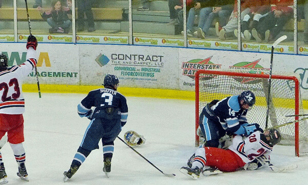 The chaos of overtime: East's Ian Mageau (23) celebrates the game-winning goal, as Blaine's Brian Broos (14) knocks Frederick Hunter Paine down on top of Bengals goalie Joe Daninger, whose helmet lended off to the side. The goal was disallowed for what the officials called "inadvertent contact with the goalie." Photo credit: John Gilbert