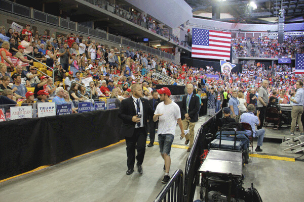 A protester inside the rally is escorted out. Photo by: Richard Thomas