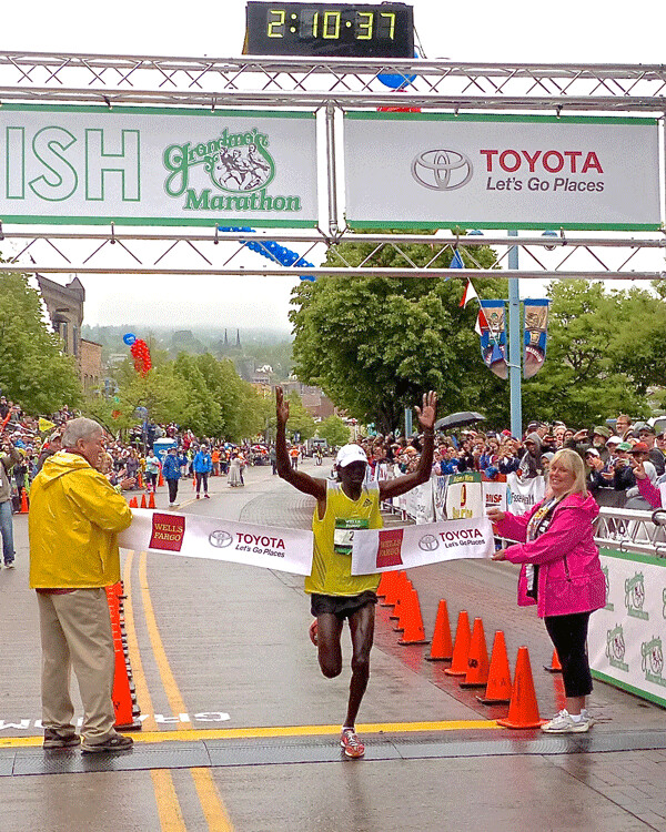 Elisha Barno broke the finish line tape to win the 2015 Grandma’s Marathon, and  nobody knew it would be the first of four consecutive championships.  Photo credit: John Gilbert