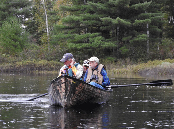 Dan Tiller and Dale Crusoe listen hard in hopes that a bull elk will bugle in response to Dan’s call, as John Maier paddles the drift boat. Photo by Emily Stone. 