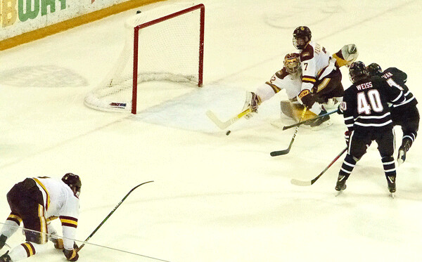 UMD's bizarre decisive goal came when goalie Hunter Shepard got the tip of his stick-blade on a shot by Nolan Sullivan (11), as defenseman Scott Perunovich was about to collide with Shepard. Nick Wolff, left, was getting to his feet just in time to send a 60-foot pass to Tanner Laderoute who scored in the closing seconds of the second period for a 2-1 lead - the winning goal in a 4-1 sweep. Photo credit: John Gilbert
