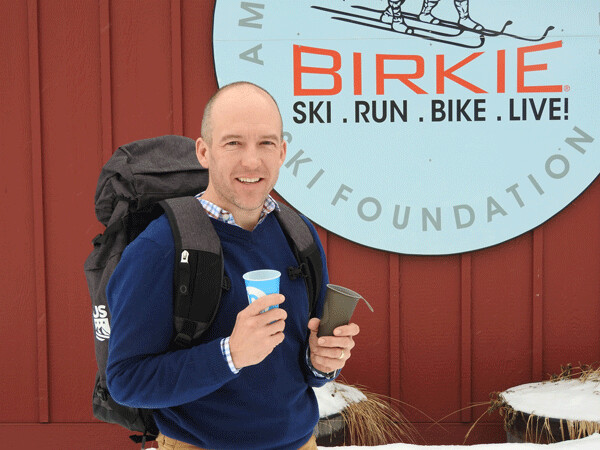 Ben Popp, Executive Director of the American Birkebeiner Ski Foundation (ABSF) shows off two initial offerings from the Birkie Green initiative—a durable gear bag and a reusable silicone cup. The Birkie continues to explore ways to reduce waste and save energy. Photo by Emily Stone.