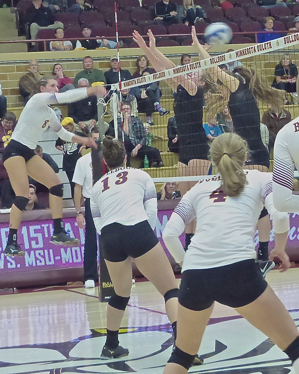 Emerging star Makenzie Morgen hammered a kill through Northern's defense, while UMD teammates Allison Olley (13) and setter Emily Torve watched. Photo credit: John Gilbe