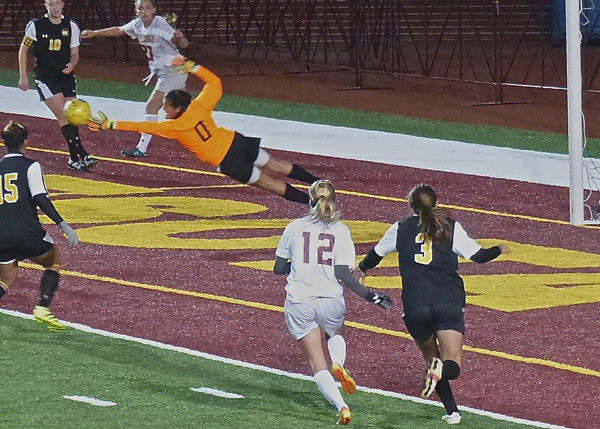 Wayne State goaltender Kylie Comba dove to block a pass to UMD’s Natalie St. Martin (12), in UMD’s 1-0 victory Friday. UMD’s final home game is Friday at 6 p.m. against Minnesota-Crookston. Photo credit: John Gilbert