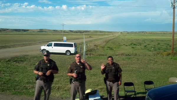 At a roadblock on county highway 1806 near Fort Lincoln, North Dakota state troopers wave our bus out the area. Movable roadblocks force activists to scout alternate routes to Standing Rock. Photo credit: Athena Houmas 