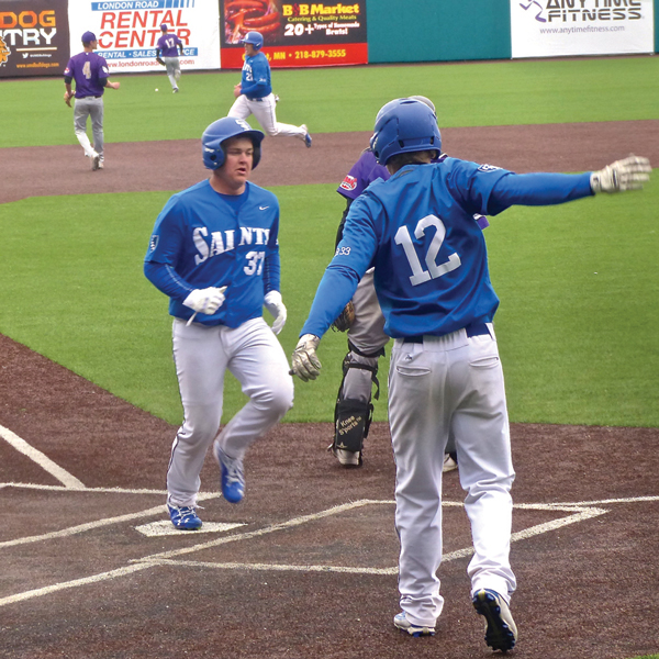 Saints Steven Neutzling (12) scored, then welcomed Conor Wollenzein home, and Chris Olson was still to come, as the ball eluded the Eagles left-fielder.  Photo credit: John Gilbert