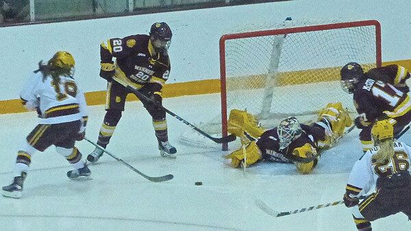UMD goalie Maddie Rooney dives to block one of her 62 saves to stop Gopher attackers Kelly Pannek and Sarah Potomac (26). Photo credit: John Gilbert