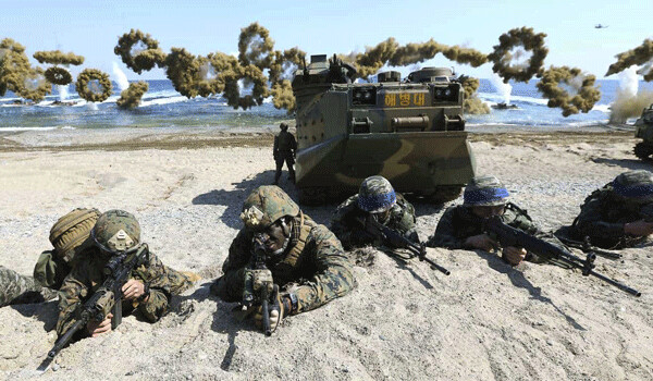 In this March 12, 2016 file photo, U.S. Marines, left, and South Korean Marines, wearing blue headbands on their helmets, take positions after landing on the beach during the joint military combined amphibious exercise, called Ssangyong, part of the Key Resolve and Foal Eagle military exercises, in Pohang, South Korea. (Kim Jun-bum/Yonhap via AP, File) KOREA OUT