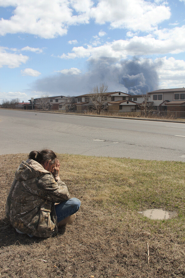 Dennis Houle prays by Hwy. 53 in Superior as smoke billows from the refinery plant. Photo by Richard Thomas