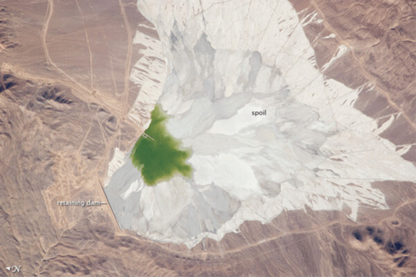 The Escondida mine tailings lagoon above – in Chile’s Atacama desert - is the world’s largest tailings pond. The tailings are intended to be held in perpetuity behind earthen retaining dams. The straight line at the left of the photo represents the tallest of the surrounding retaining walls, and is 0.6 miles long. NASA satellite photo.