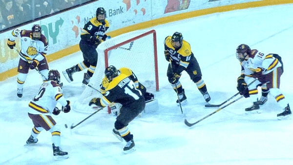 UMD’s balance included the hustling fourth line of Kobe Roth (10), Jade Miller (behind net) and Billy Exell (26), surrounding CC goalie Ale LeClerc. Photo credit: John Gilbert