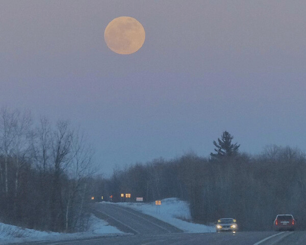 The rare Wolf/Blood Moon rising seemed larger than the vehicles on Hwy. 210, as it provided a welcome beacon. Photo credit: John Gilbert