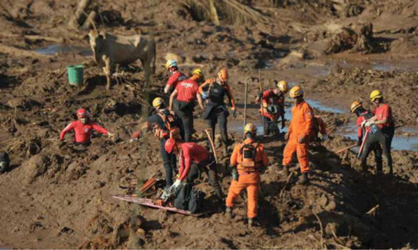 Rescue workers futilely searching for bodies buried in the soon-to-harden sludge. Note the worker to the left unable to excape from his waist-deep predicament