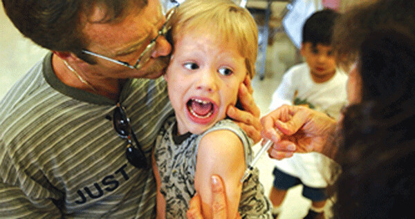 Incoming kindergartener Jeremy Conner, 5, reacts to a Measles, Mumps and Rubella vaccination (MMR) as his father Mark Conner tries to comfort him August 26, 2002 in Santa Ana, California.  (Note the improperly sited and administered vaccination [vaccinations are to be given intramuscularly – not subcutaneously – and into the deltoid muscle - not the triceps].) (Photo:  David McNew/Getty Images)