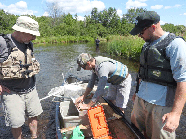 Mike, Jake and Max measure the length of a smallmouth bass. It has already been tagged, and will be released with the hope of being recaptured in the future. Photo by Emily Stone. 