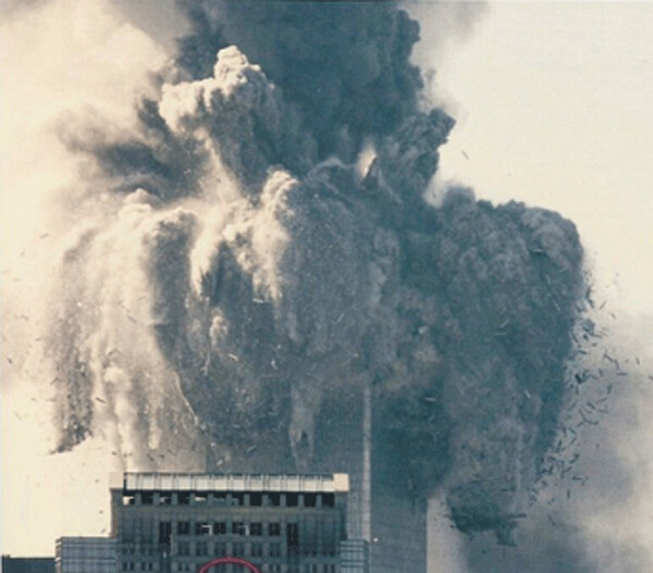 Photo of the initiating explosion at the top of one of the Twin Towers, that brought each of them down, at freefall speed, on 9/11/01. Note that the fine concrete dust/debris is exploding upwards and outwards and not just falling down. The little splinters are actually 30 foot-long  portions of the many massive steel beams and columns that had been sectioned by cutter charges into “convenient” lengths, which is one of the goals of all controlled demolition experts (for ease in carting away the remains of steel framed buildings after being explosively demolished)