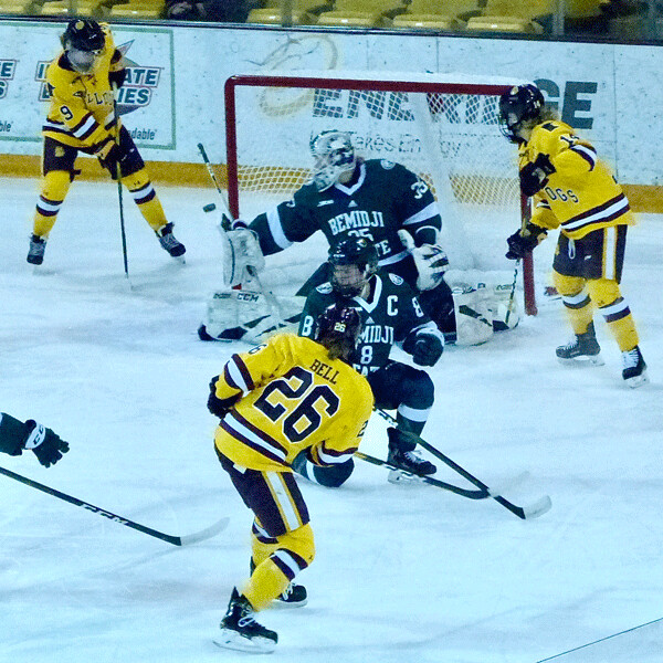 Ashton Bell, who scored UMD's first goal in the 2-0 Cup final, had her shot deflected wide by Bemidji State goalie Lauren Bench as Anna Klein, left, and Sydney Brodt, right, sought the rebound. Photo Credit: John Gilbert