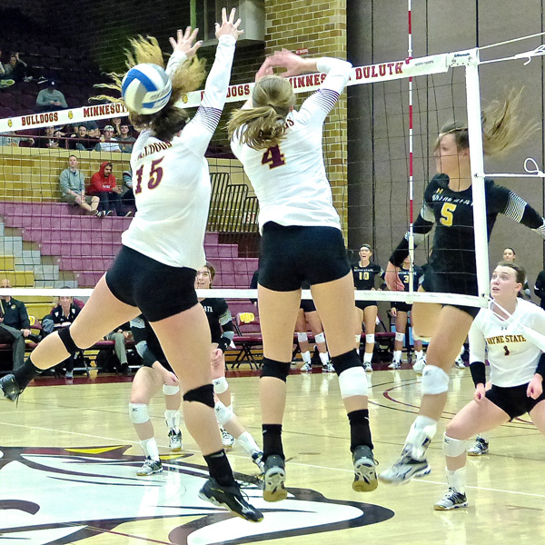 Wayne State's Michaela Mesti (5) squeezed a kill through UMD blockers Sydnie Mauch (15) and Emily Torve (4) as Wayne rallied to win the last three sets. Photo credit: John Gilbert