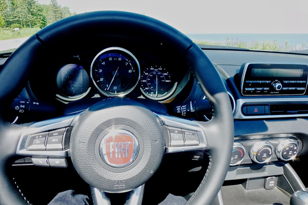 Inside, the steering wheel and driver controls are links to our sports-car-driving heritage. Photo credit: John Gilbert