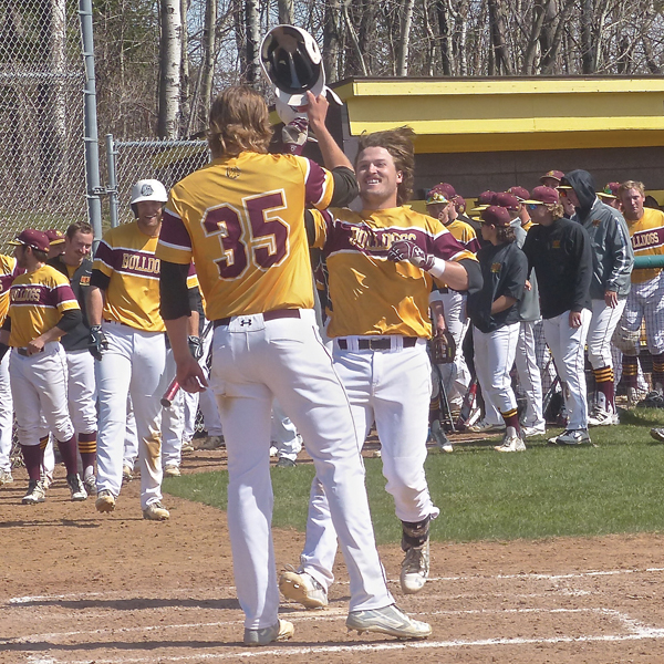 Senior Alex Wojciechowski (35) and his freshman brother, Tyler (21) formed UMD’s welcome party for senior Jimmy Heck, who delivered his 15th homer against Minot. Photo credit: John Gilbert