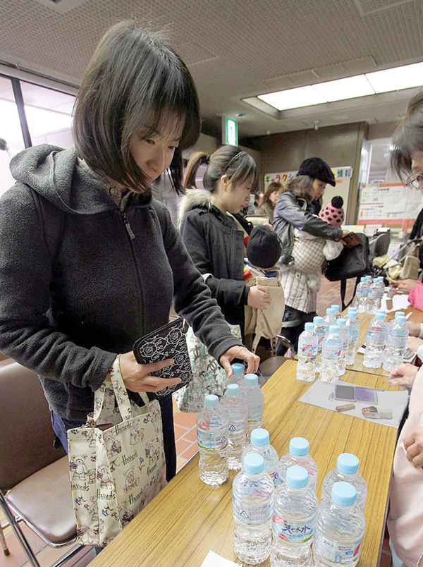 Mothers receive bottles of water at a distribution office in the Adachi ward of Tokyo, Japan, on March 24, 2011. Japanese beverage makers faced renewed pressure to raise bottled-water production after radiation from the Fukushima radiation disaster contaminated Tokyo’s water supply. Photographer: Haruyoshi Yamaguchi/Bloomberg via Getty Images.