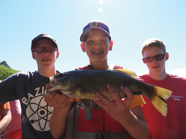George and Joe Tuttle (ends) and Nolan Arthur (center) show off a big bass. Photo by Emily Stone.